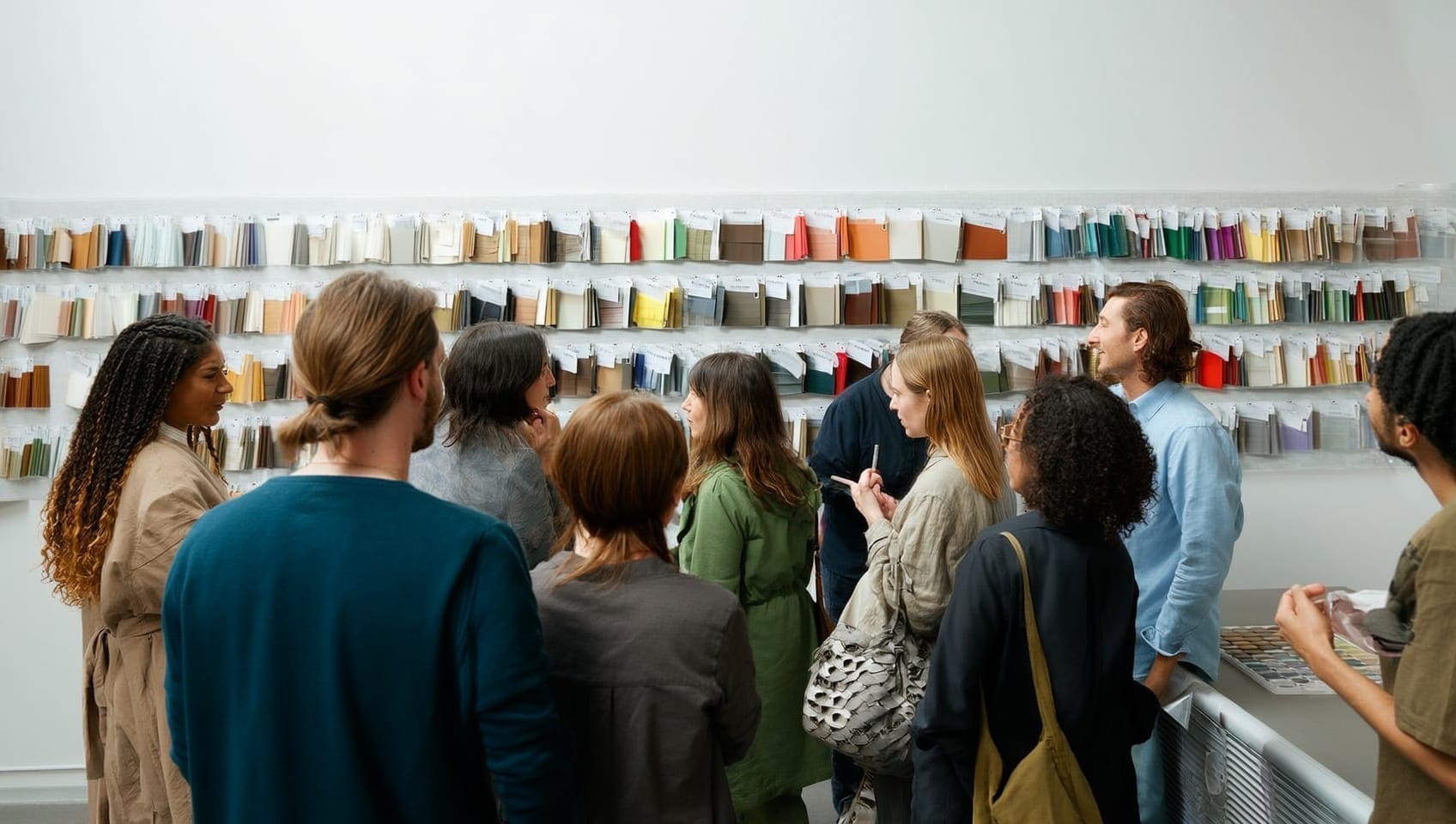 JULY designers studying rows of color and material studies pinned across a studio wall