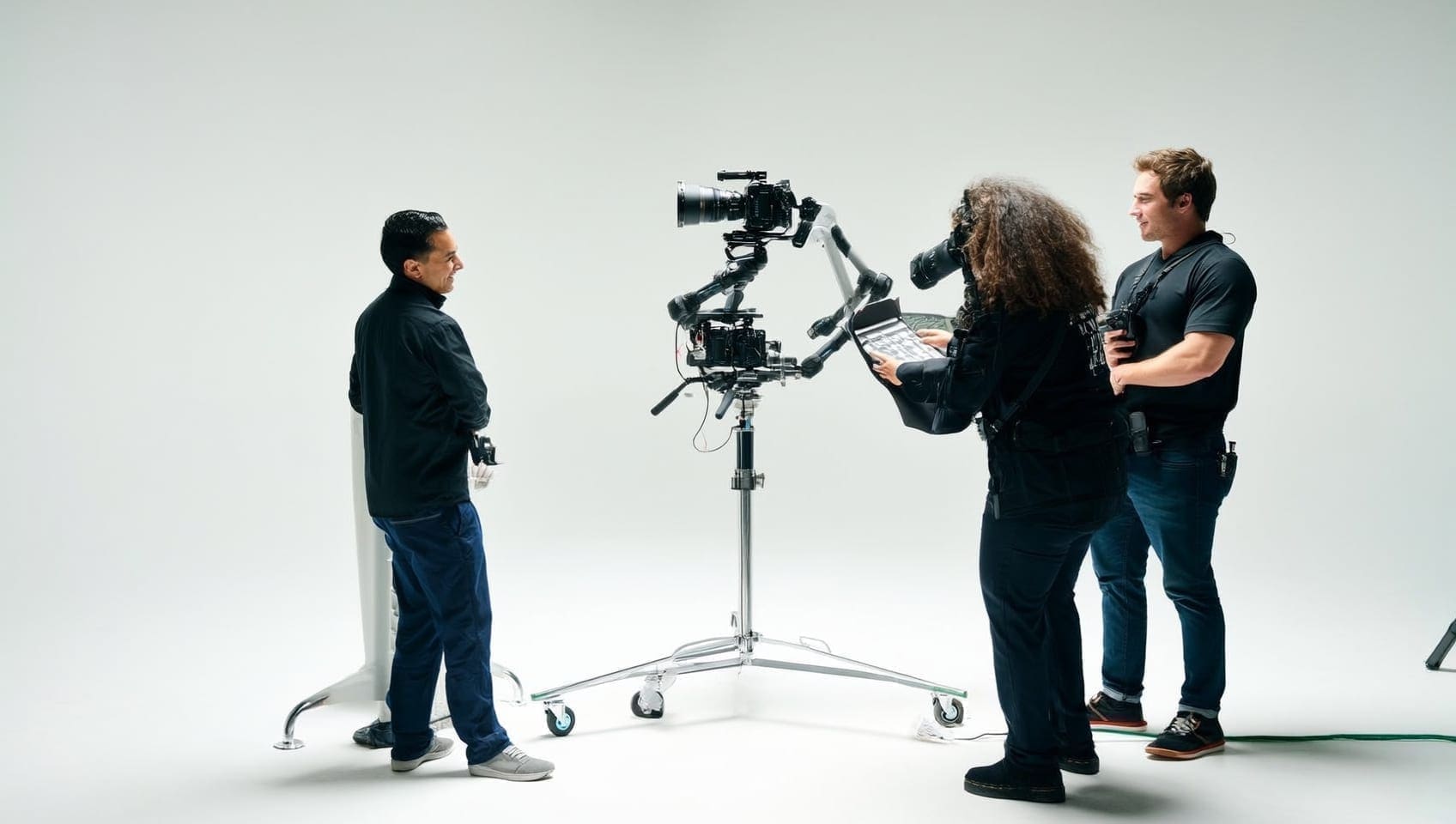 Camera operator framing a shot on a gimbal rig while a producer checks the shot list