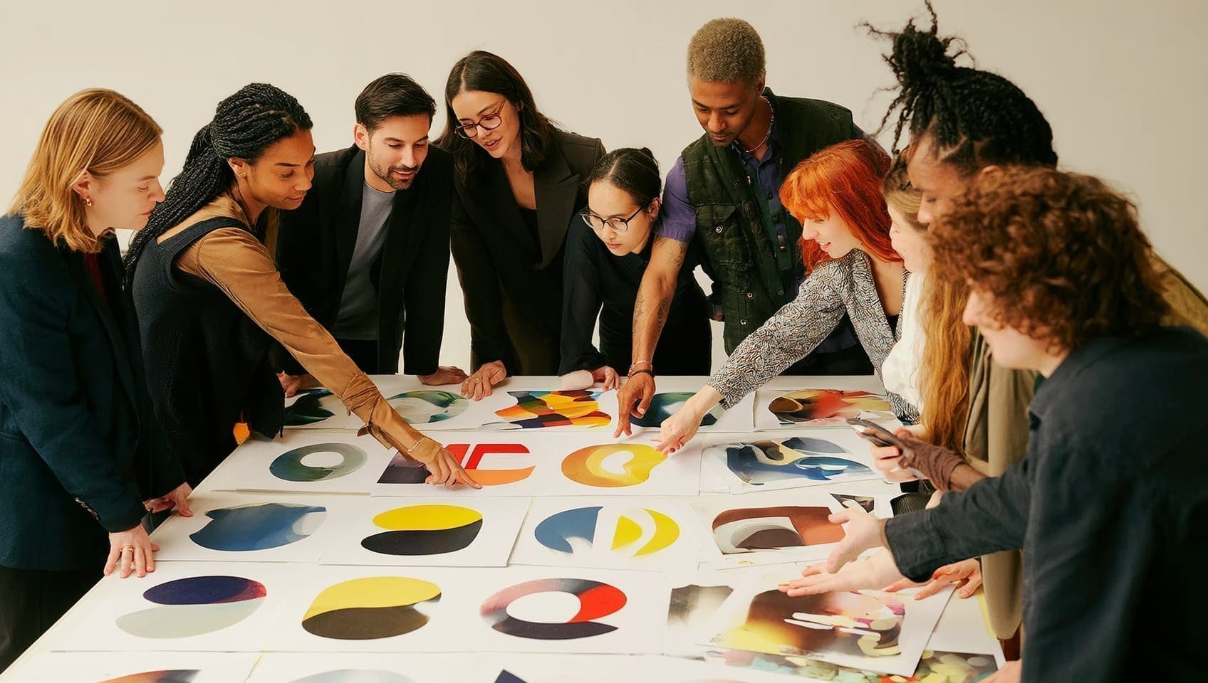 Creative team reviewing bold campaign layouts spread across a studio table