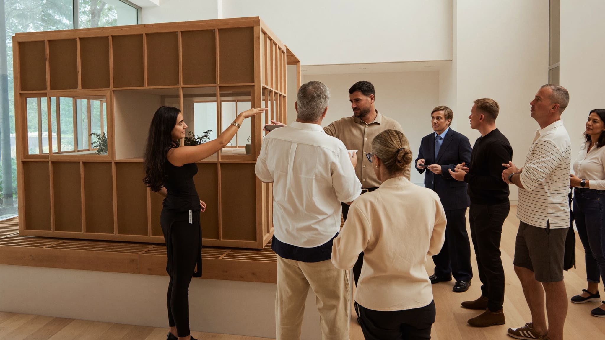 A sales team of different backgrounds presenting a development project to visitors inside a bright presentation gallery