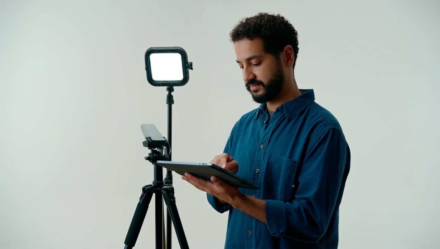 Social manager reviewing a content calendar on a tablet beside a phone tripod rig