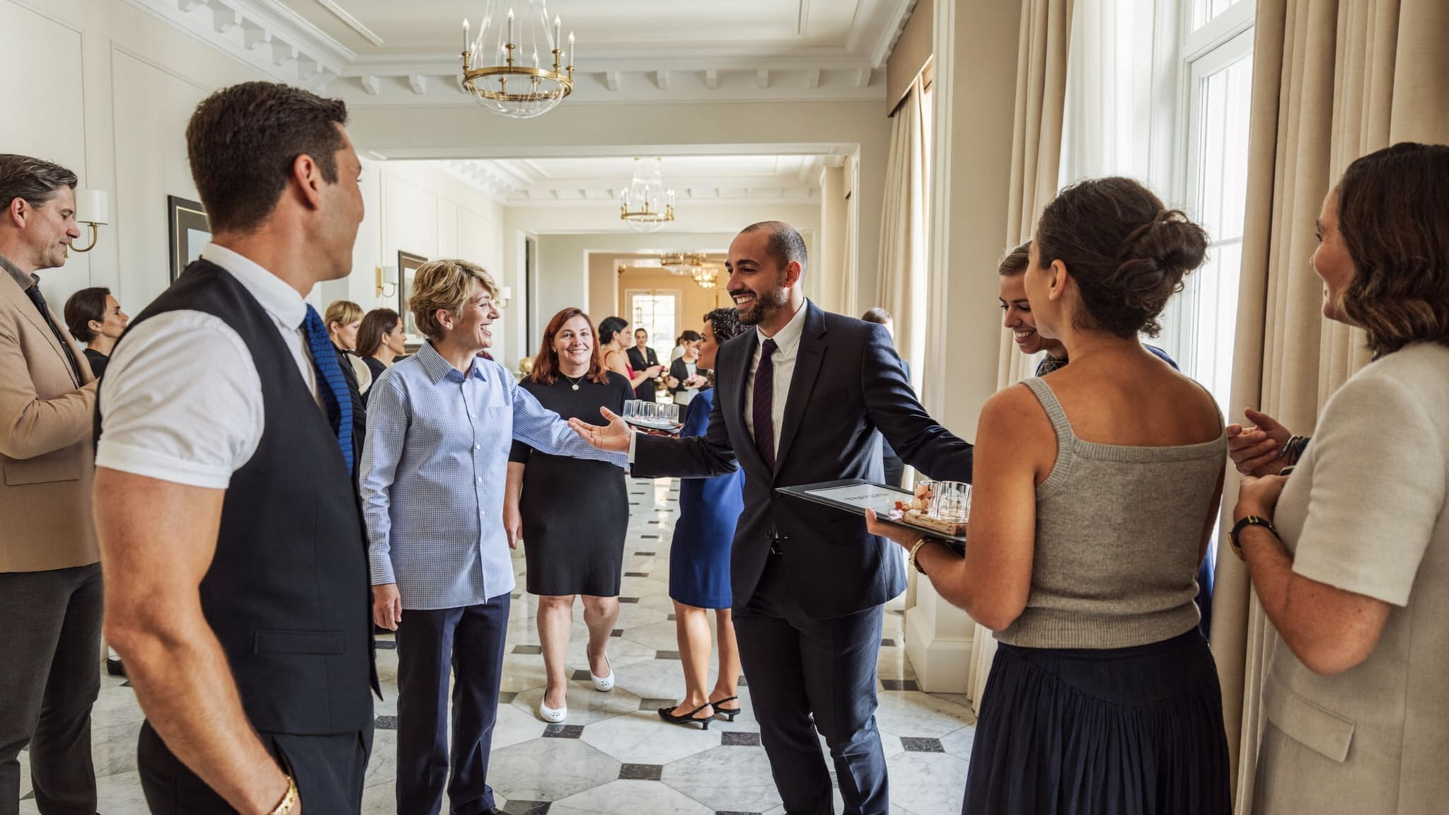 A hotel concierge of any background warmly greeting arriving guests in a bright, welcoming lobby